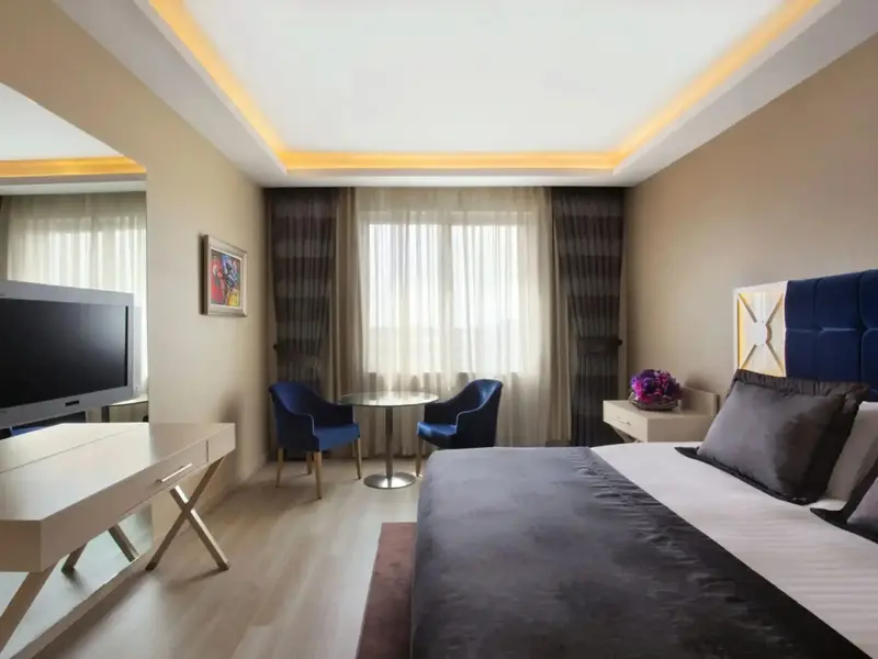 Une chambre lumineuse avec un lit et un coin salon près de la fenêtre.