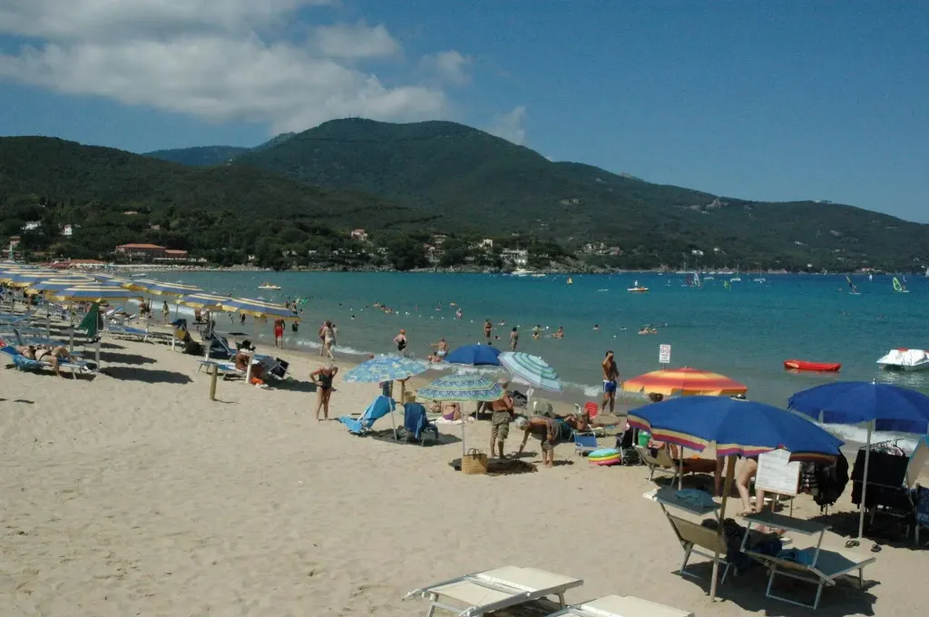 Une plage ensoleillée avec des parasols et des transats face à la mer.
