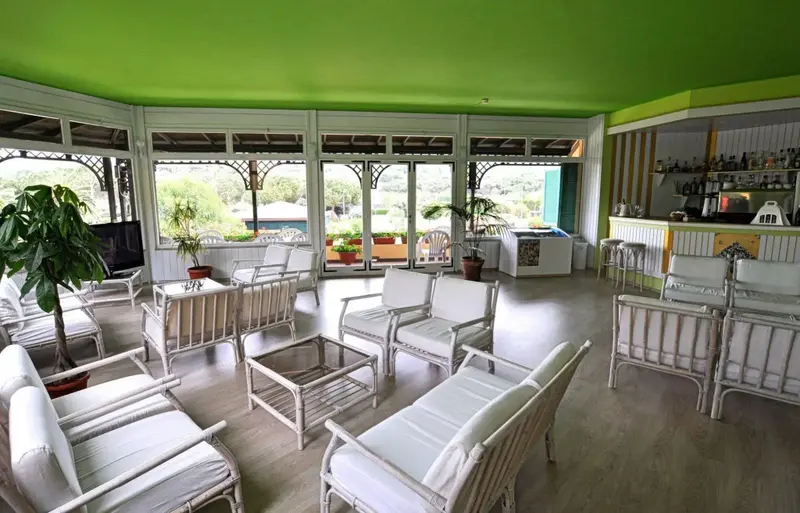 Espace de détente lumineux avec mobilier blanc et vue sur la végétation.