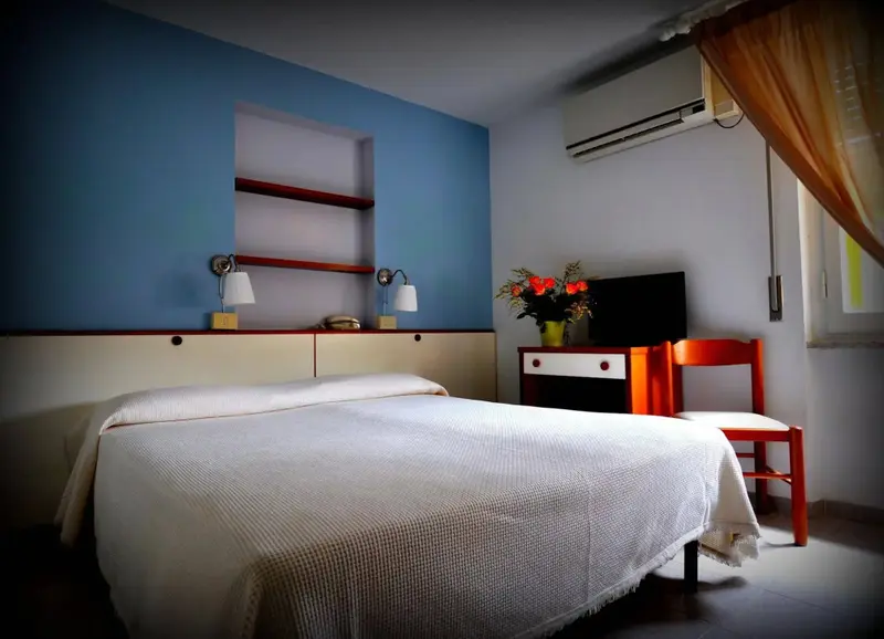 Une chambre lumineuse avec un lit blanc et des murs bleus.