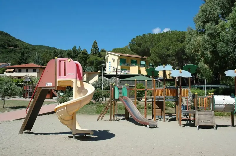 Aire de jeux colorée avec toboggans et structures en bois sur sol sablonneux.