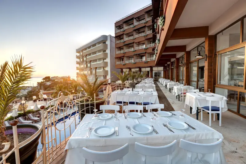 Une terrasse de restaurant avec des tables dressées face à la mer.