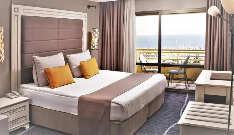 Une chambre lumineuse avec un grand lit et un balcon donnant sur la mer.