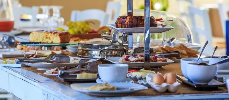 Une table garnie de viennoiseries, de fruits et de charcuteries.