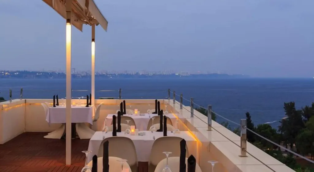 Tables dressées en extérieur avec vue sur la mer au crépuscule.