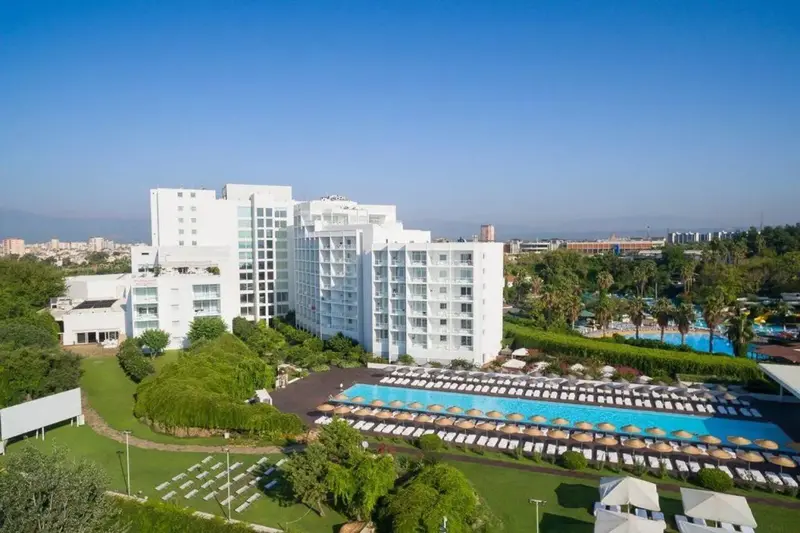 Vue aérienne d'un complexe hôtelier blanc avec des piscines et des espaces verts.