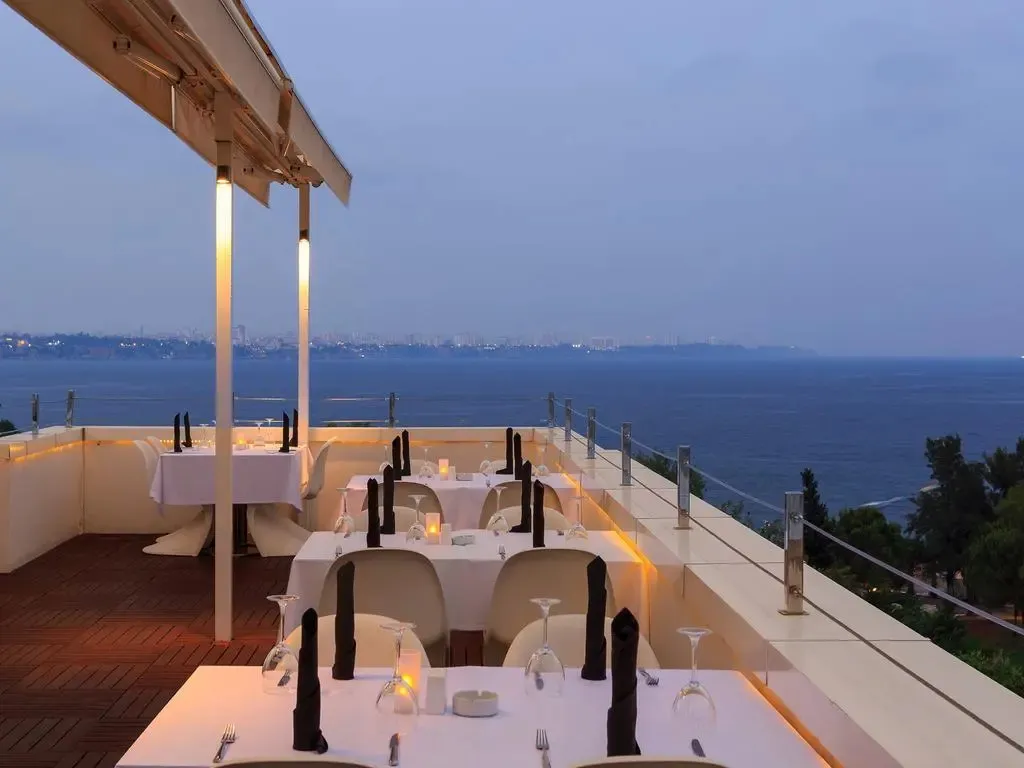 Tables dressées en extérieur avec vue sur la mer au crépuscule.