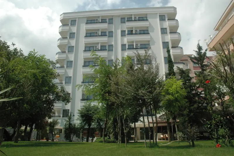 Bâtiment blanc à plusieurs étages entouré de végétation et d'une pelouse verte.