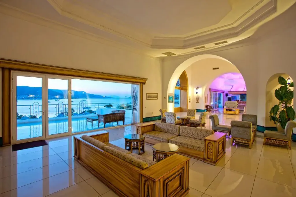 Espace de détente intérieur avec canapés et vue sur la mer par de grandes baies vitrées.