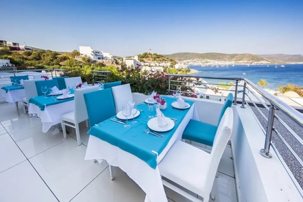 Tables dressées sur une terrasse avec vue sur la mer et la côte.