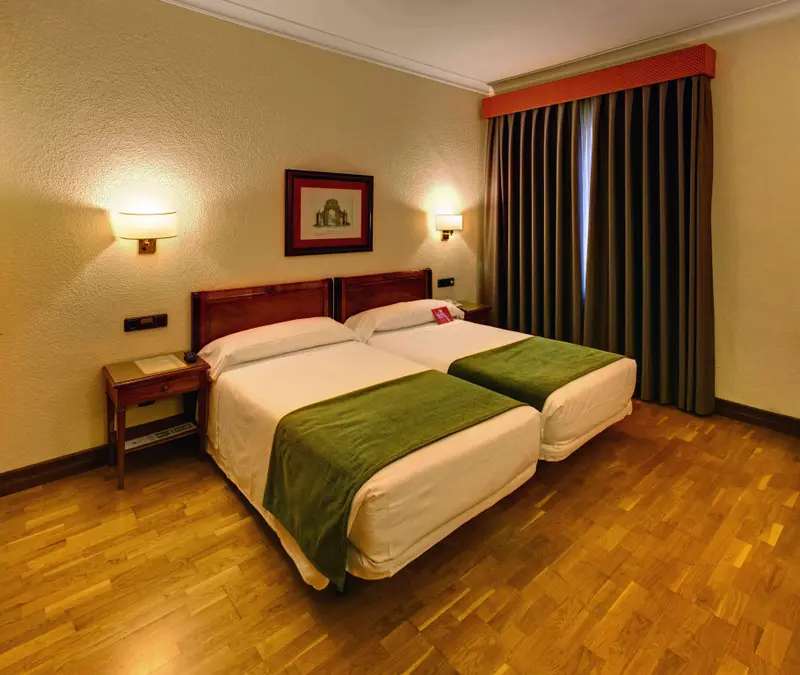 Une chambre lumineuse avec deux lits simples et une décoration sobre.