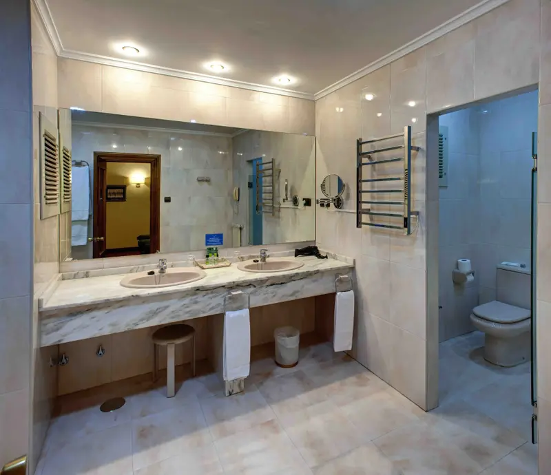 Une salle de bain lumineuse avec deux vasques en marbre et un grand miroir.