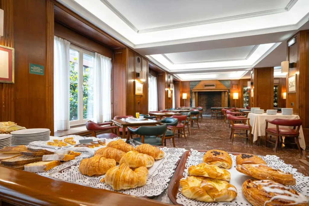 Une salle lumineuse présente des tables dressées avec des viennoiseries et des boissons.
