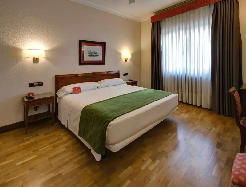 Une chambre lumineuse avec un grand lit recouvert d'une couverture verte.