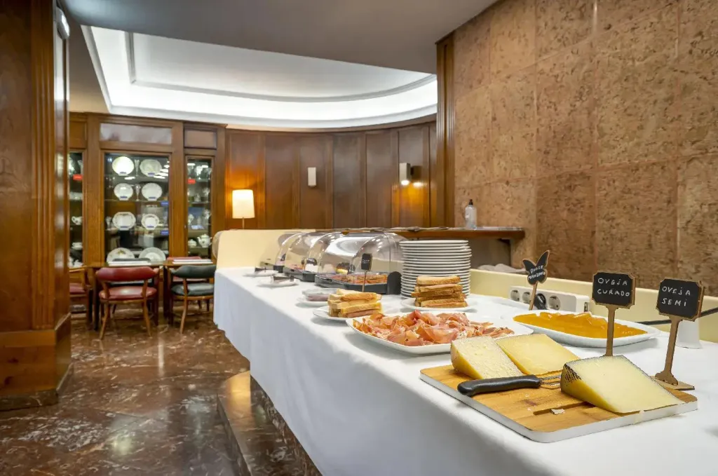 Un buffet propose une variété de charcuteries et de fromages dans une salle lumineuse.