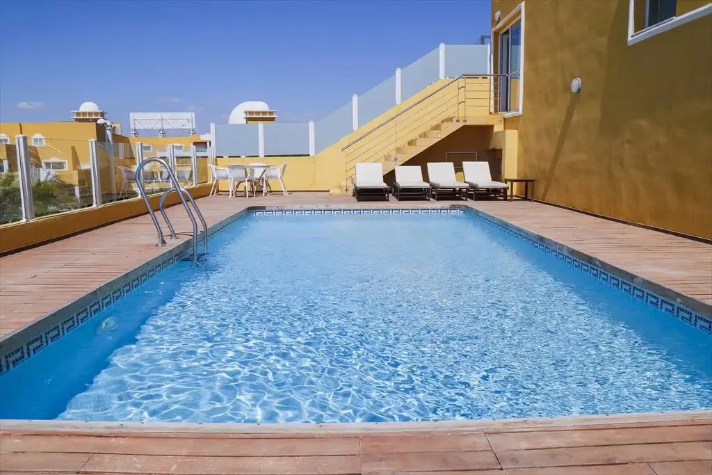 Une piscine rectangulaire avec des transats sur une terrasse en bois.