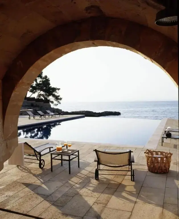 Vue sur une piscine à débordement donnant sur la mer depuis une arche.