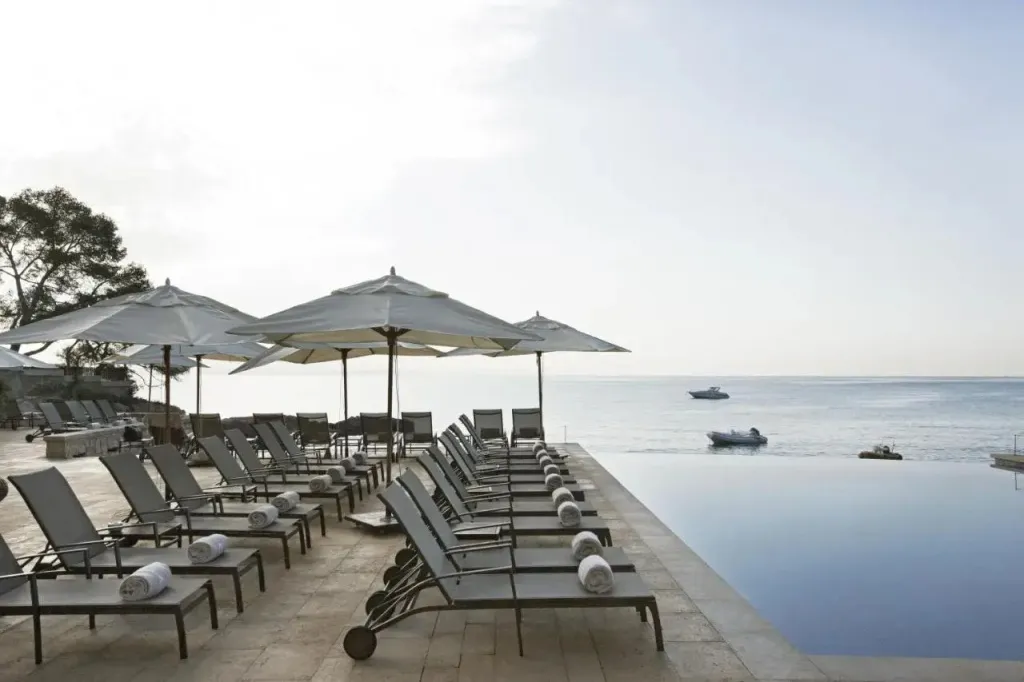 Transats alignés au bord d'une piscine à débordement avec vue sur la mer.