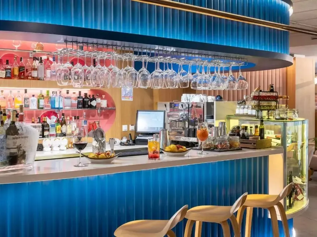 Un comptoir de bar moderne avec des bouteilles colorées et des verres suspendus.