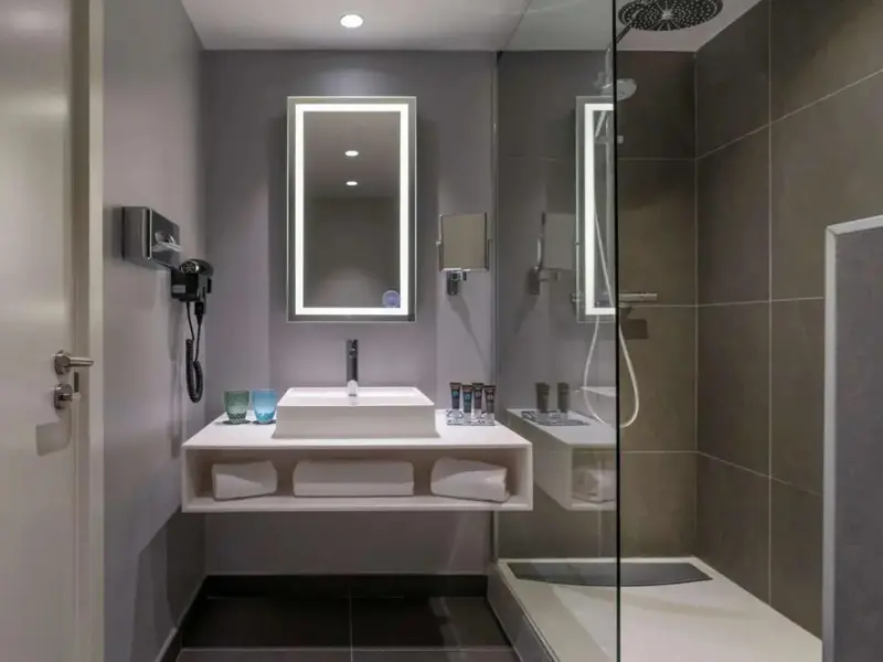 Une salle de bain moderne avec douche à l'italienne et grand miroir lumineux.
