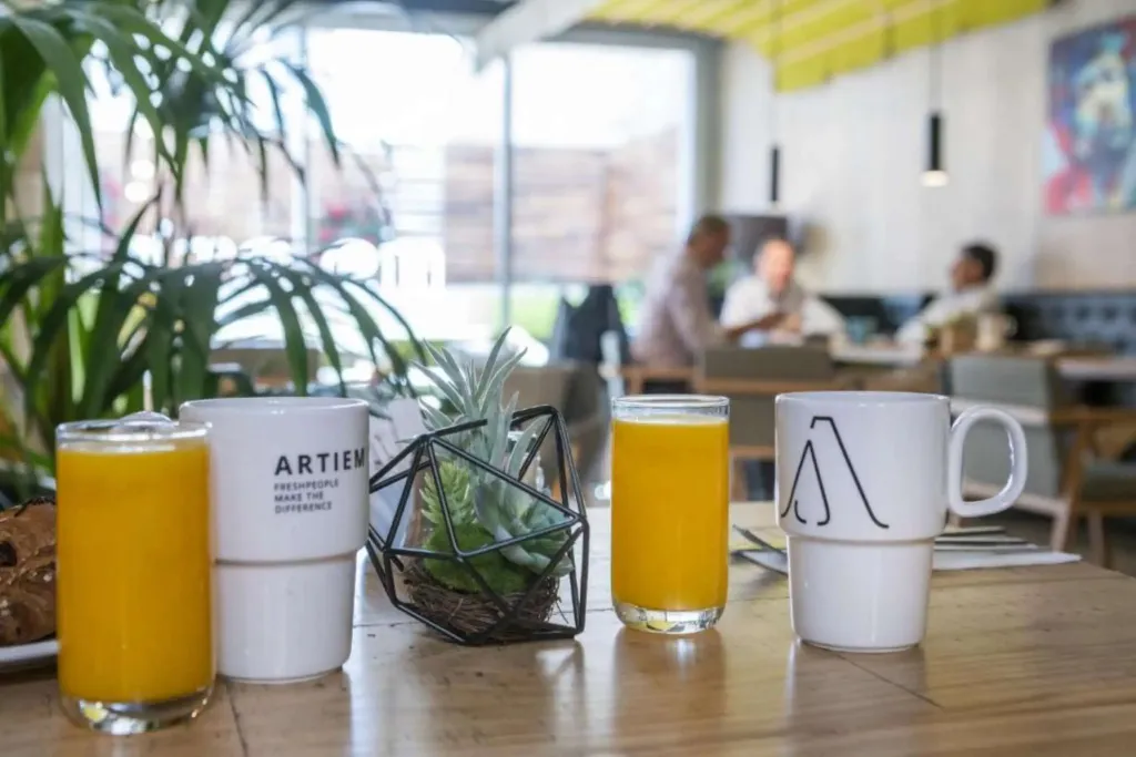 Une table en bois présente des verres de jus d'orange et des tasses à café.