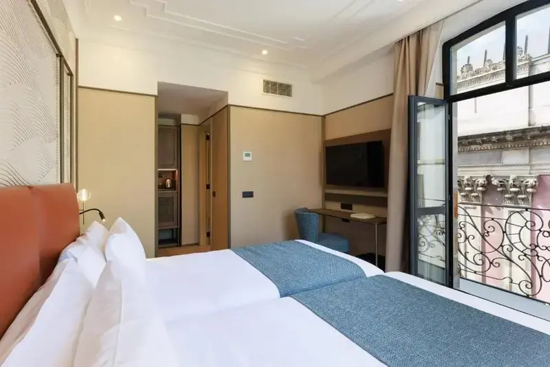 Une chambre lumineuse avec un grand lit et un balcon.