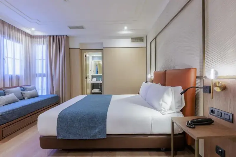 Une chambre lumineuse avec un grand lit et un coin salon.