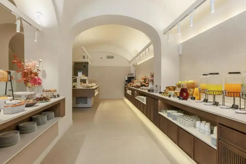 Un long buffet propose une variété de plats et de boissons dans une salle voûtée.