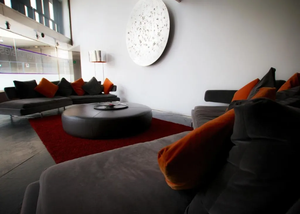 Espace de détente intérieur avec canapés et tapis rouge.