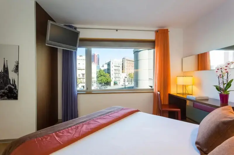 Une chambre lumineuse avec un grand lit et une vue sur la ville.