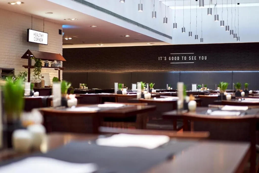 Une salle de restaurant spacieuse avec des tables dressées et une décoration moderne.
