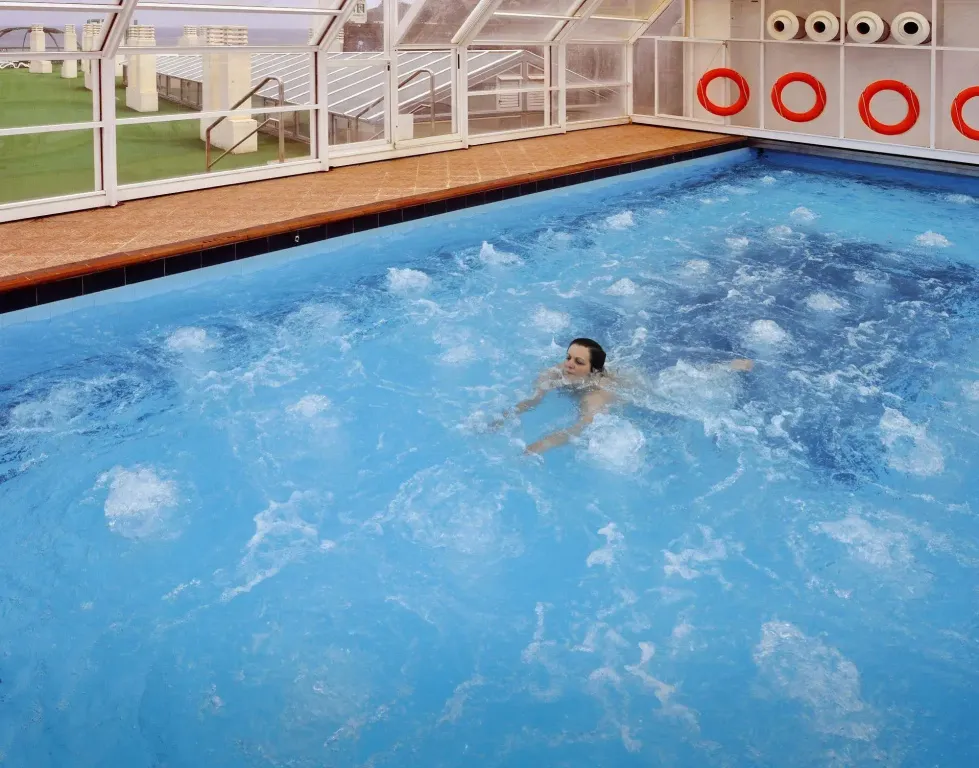 Une personne nage dans une piscine intérieure.