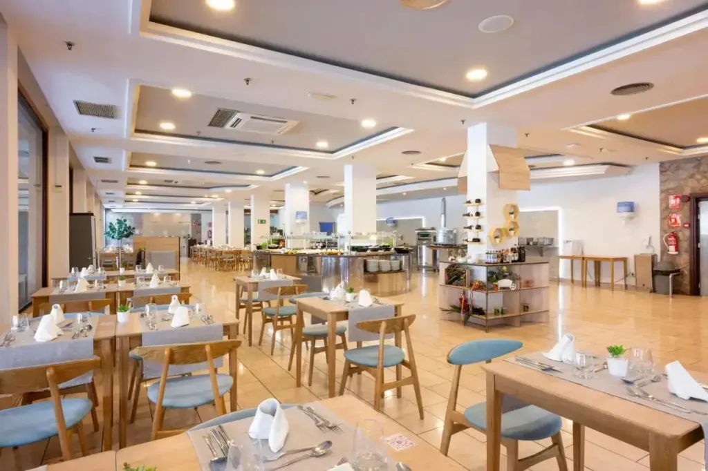 Une salle lumineuse avec des tables dressées pour le repas.