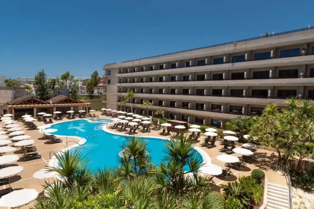 Une piscine turquoise bordée de transats sous le soleil.