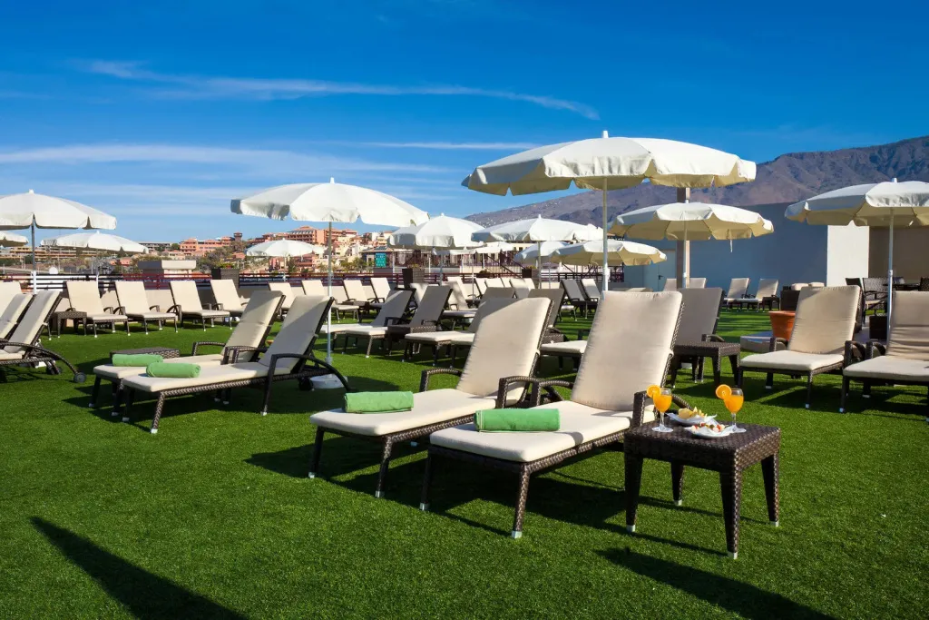 Transats et parasols sur une terrasse avec vue sur la mer et les montagnes.