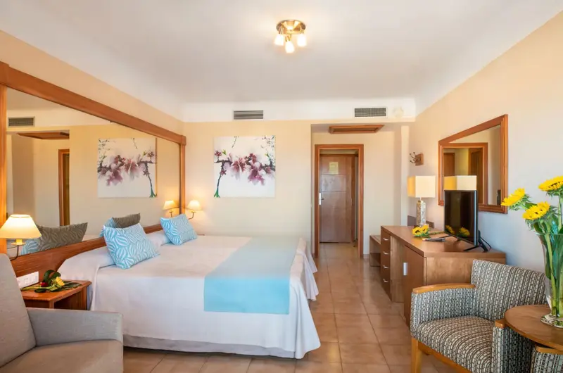 Une chambre lumineuse avec un lit double et un coin salon.