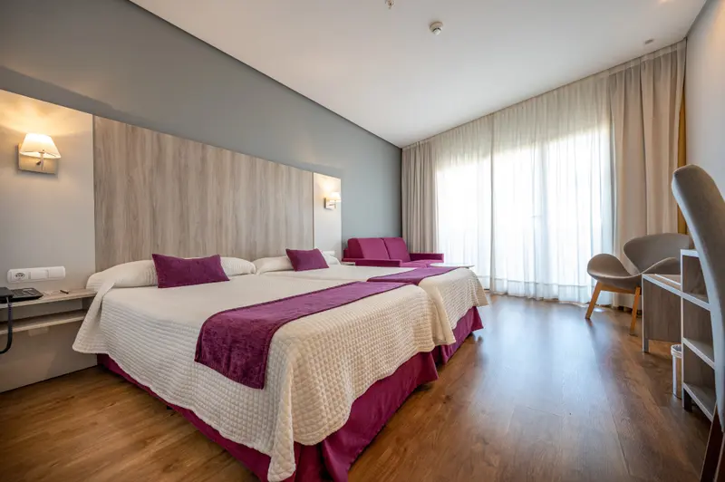 Une chambre lumineuse avec un grand lit et un espace détente près d'une fenêtre.