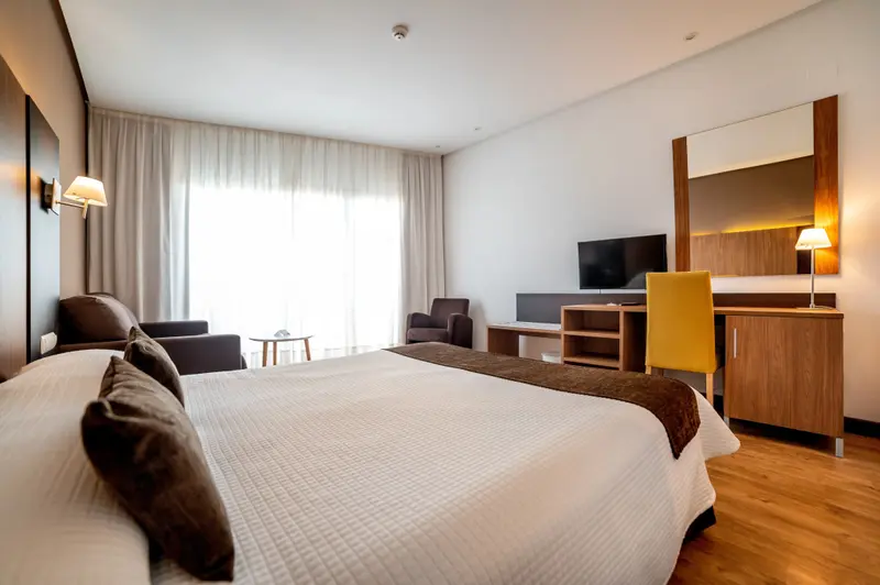 Une chambre lumineuse avec un grand lit et un coin salon.