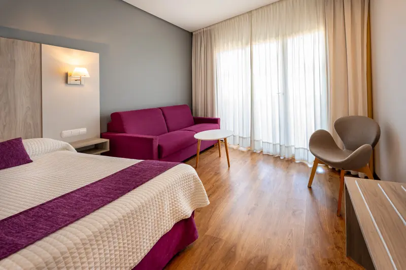 Une chambre lumineuse avec un lit, un canapé et un fauteuil.