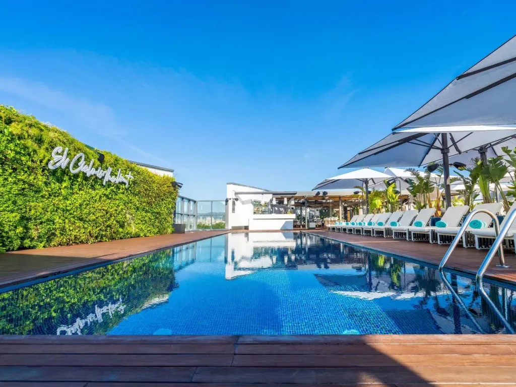 Une piscine rectangulaire avec des transats et un mur végétal en arrière-plan.