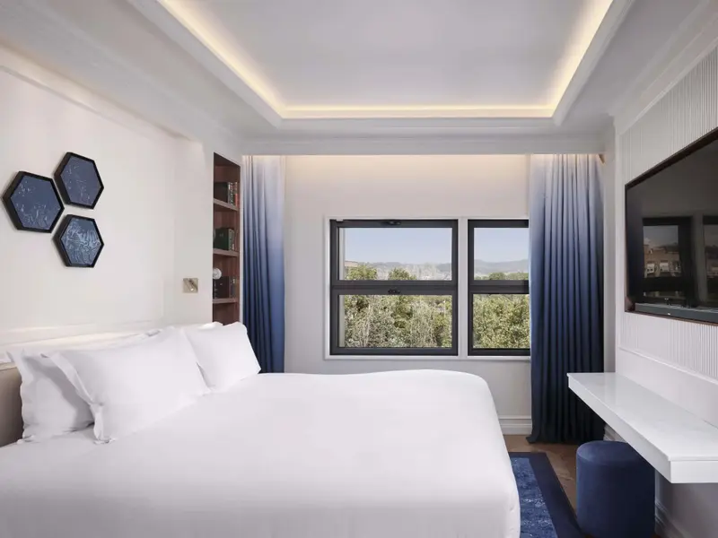 Une chambre lumineuse avec un grand lit et une vue sur un paysage verdoyant.