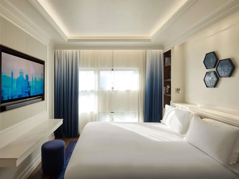 Une chambre lumineuse avec un grand lit et une télévision murale.
