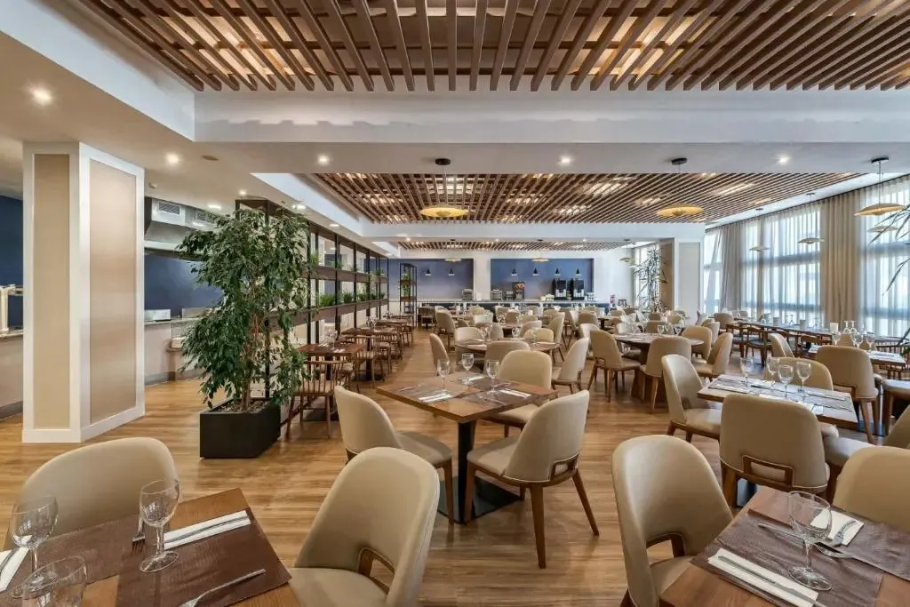 Une salle lumineuse et spacieuse est aménagée avec des tables dressées pour le repas.