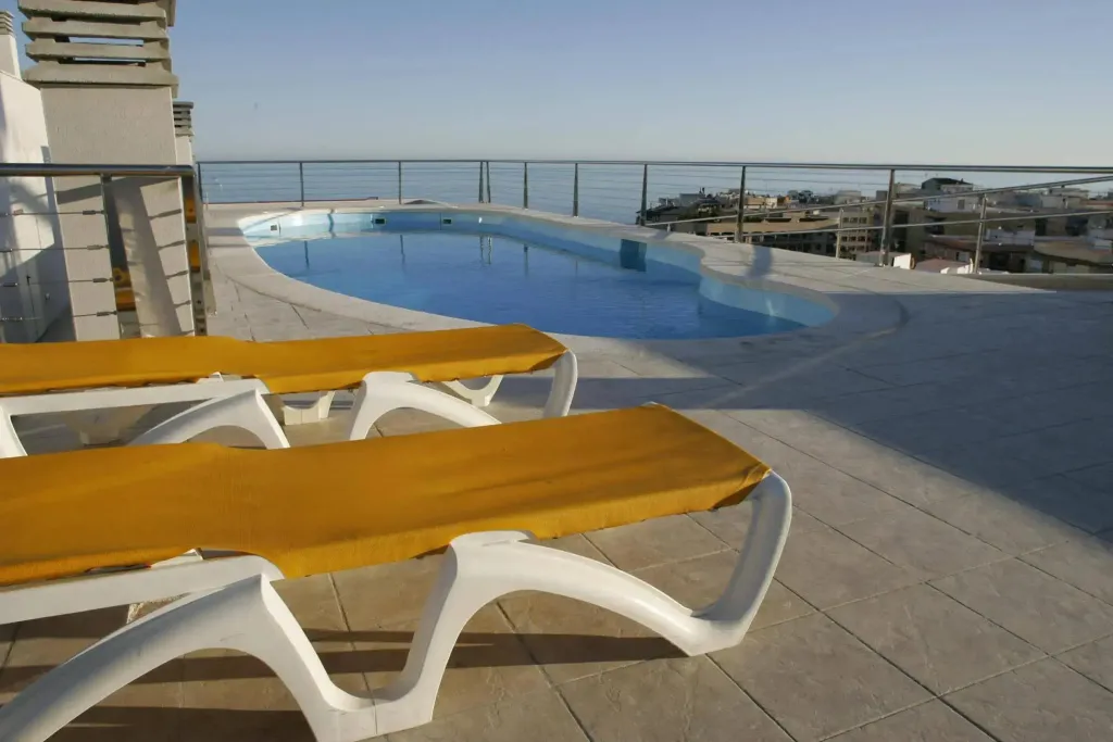 Transats oranges au bord d'une piscine avec vue sur la mer.