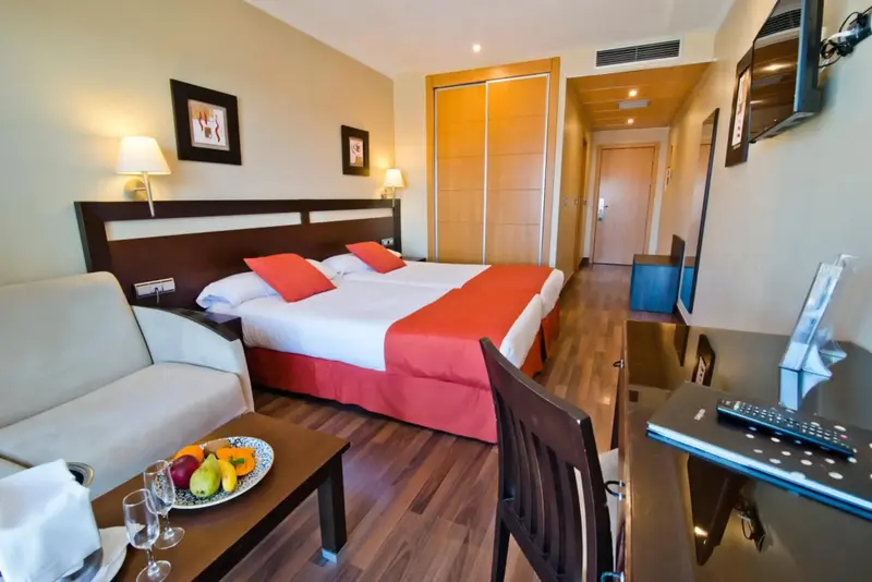 Une chambre lumineuse avec un lit double et un coin salon.