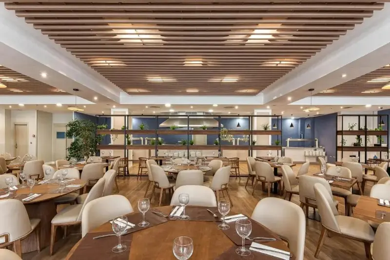 Une salle lumineuse avec des tables dressées pour un repas.