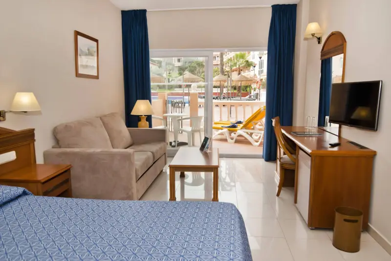 Espace de vie intérieur lumineux avec canapé et accès à une terrasse ensoleillée.