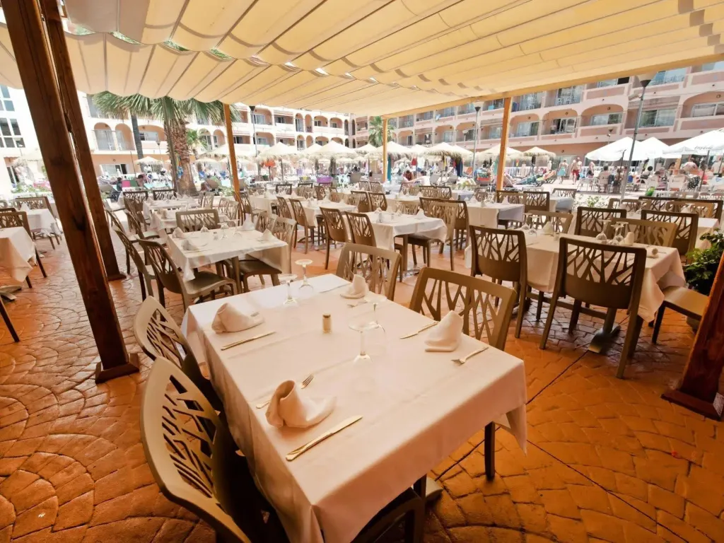 Une salle à manger extérieure avec des tables dressées pour le service.