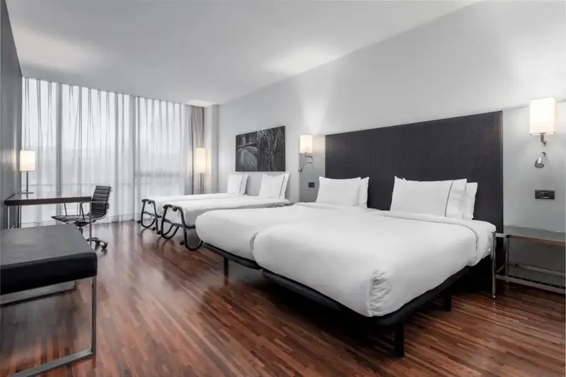 Une chambre moderne avec deux lits simples et un bureau.