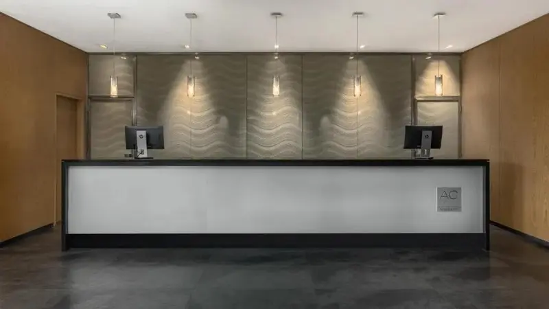 Un comptoir d'accueil moderne avec deux ordinateurs et un mur décoratif.